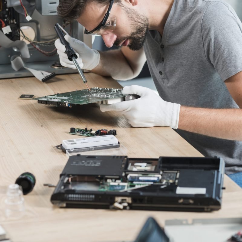 male-technician-repairing-computer-motherboard-wooden-desk